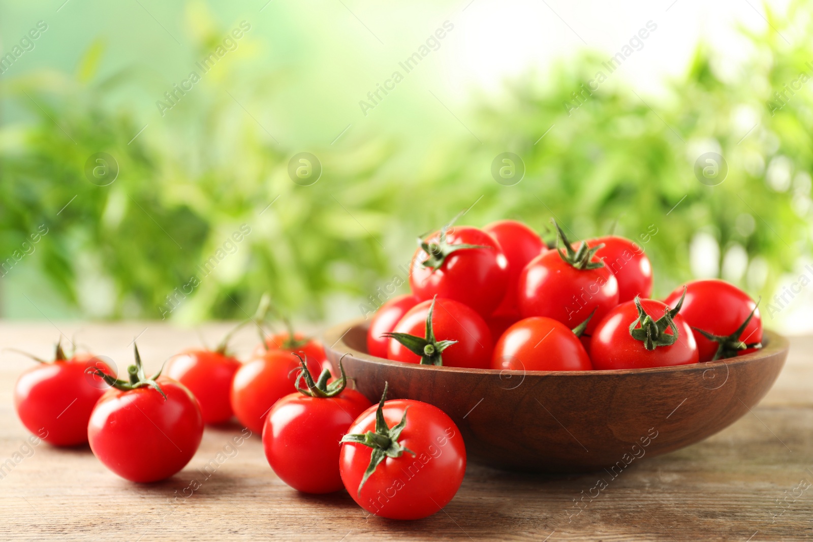 Photo of Bowl of fresh cherry tomatoes on wooden table