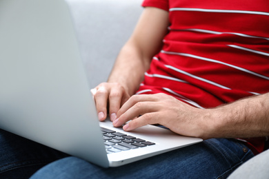 Photo of Man working on modern laptop at home, closeup