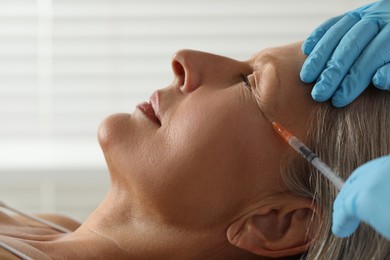 Photo of Doctor giving facial injection to senior woman in clinic, closeup. Cosmetic surgery