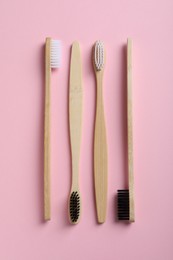 Bamboo toothbrushes on pink background, flat lay