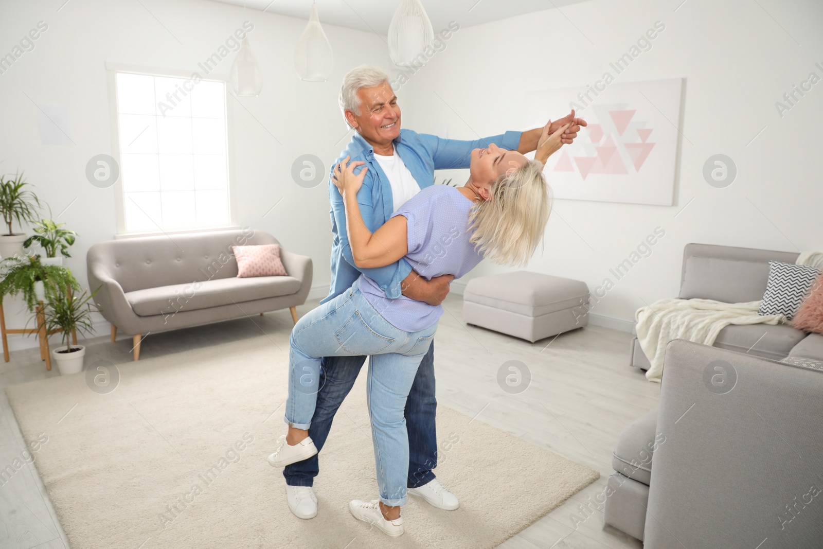 Photo of Happy mature couple dancing together in living room