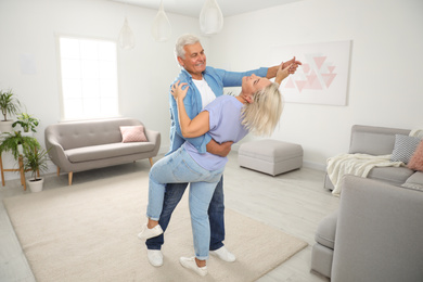 Happy mature couple dancing together in living room