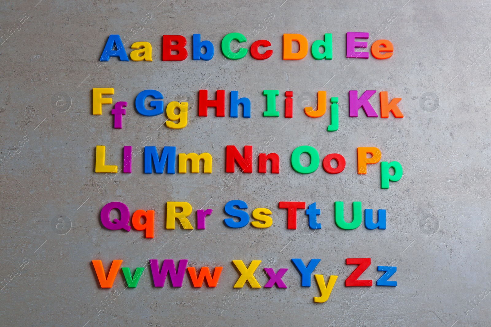 Photo of Colorful magnetic letters on grey stone background, flat lay. Alphabetical order