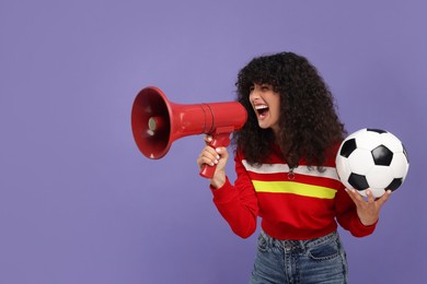 Photo of Happy fan holding soccer ball and using megaphone on violet background, space for text