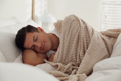 Photo of Man covered with warm beige plaid lying in bed indoors