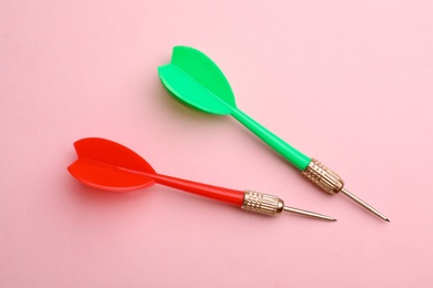 Photo of Plastic dart arrows on pink background, flat lay