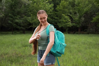 Woman applying insect repellent onto arm in park. Tick bites prevention