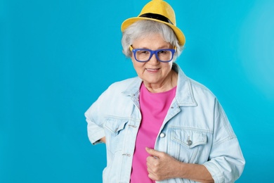 Portrait of mature woman in hipster outfit on color background