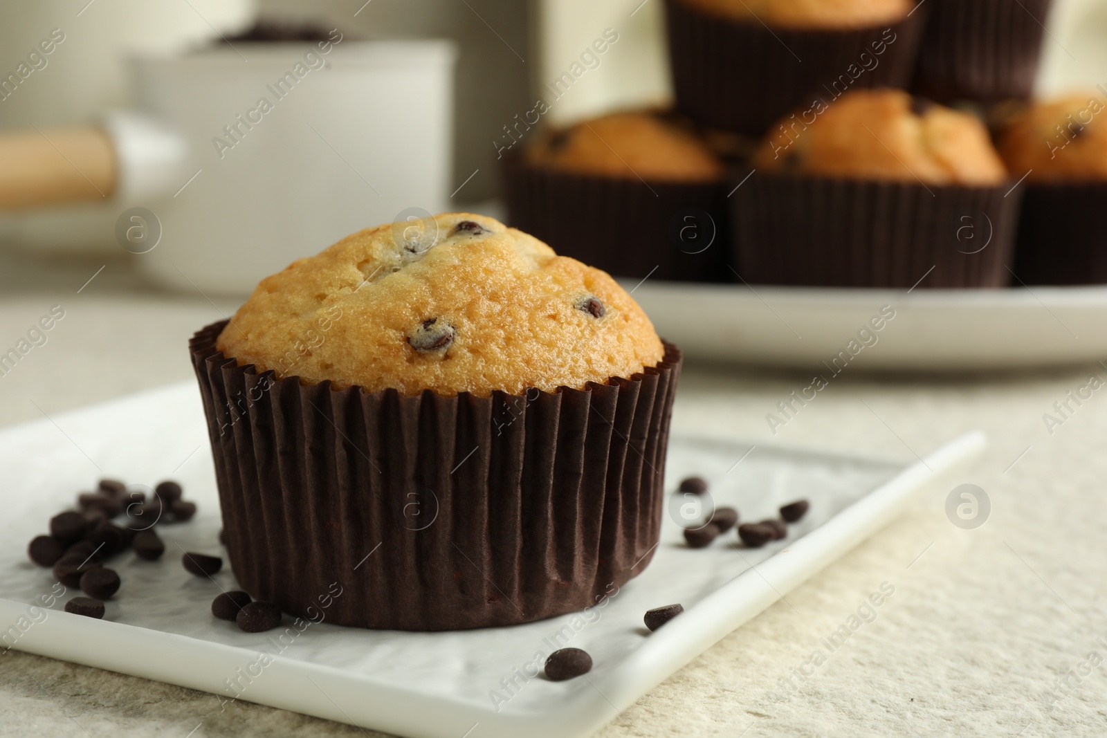 Photo of Delicious sweet muffin with chocolate chips on light textured table, closeup. Space for text