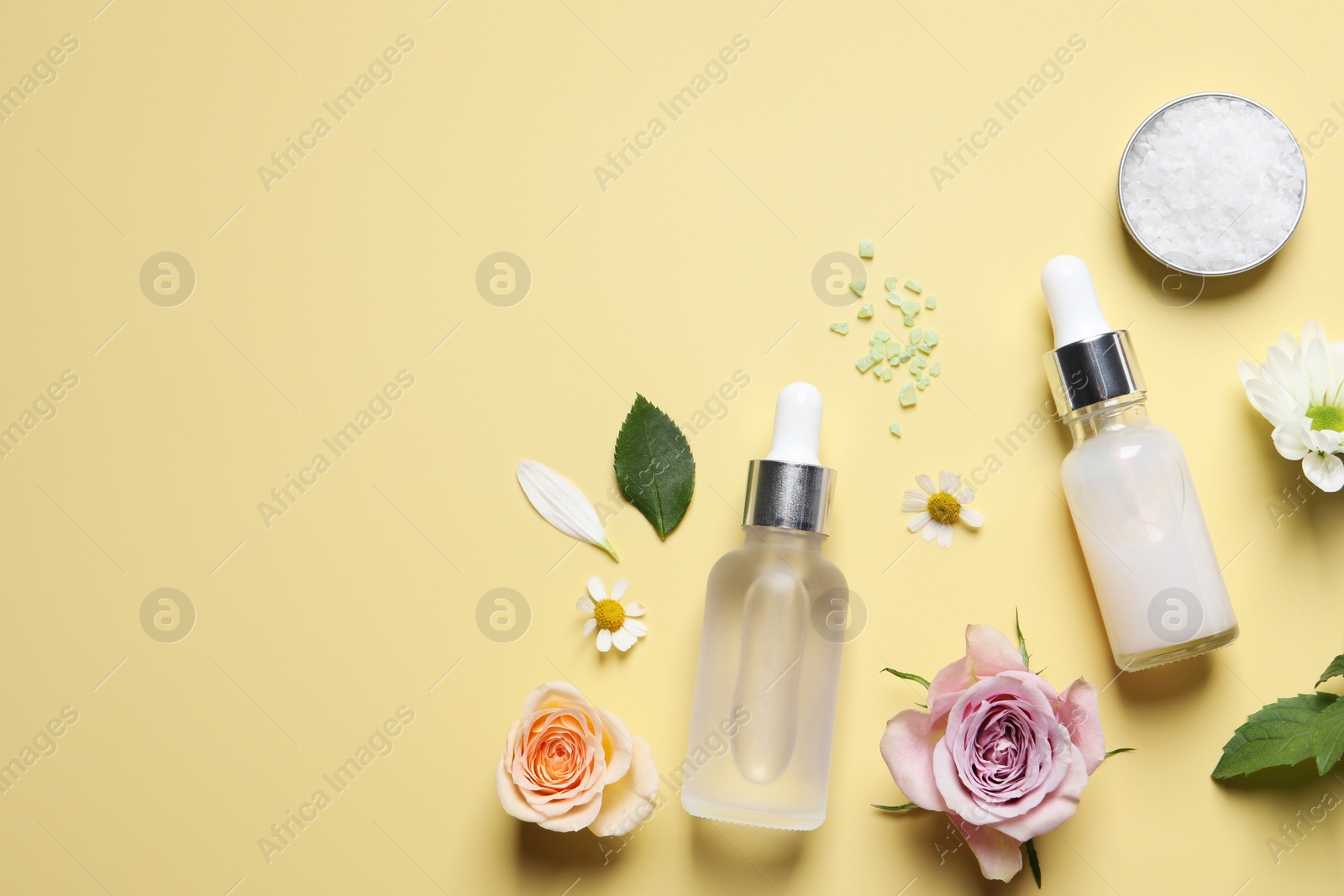 Photo of Flat lay composition with cosmetic serums on pale yellow background. Space for text
