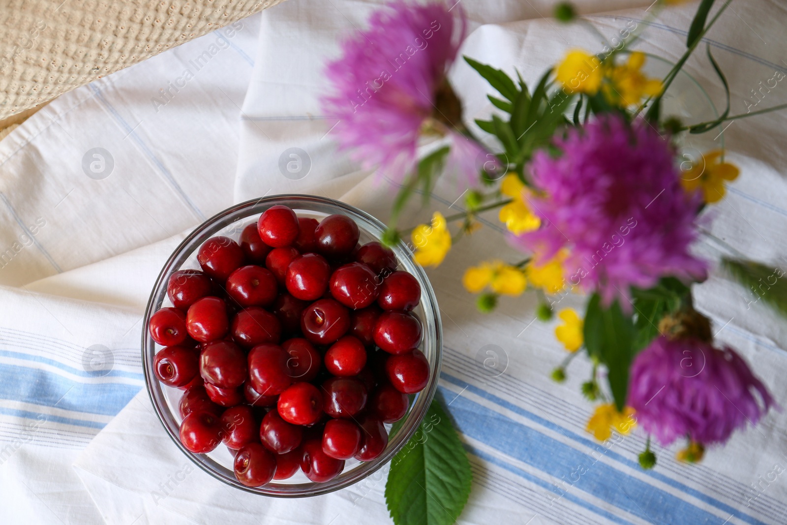 Photo of Sweet cherries and bouquet of beautiful wildflowers on table, flat lay