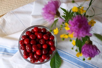 Photo of Sweet cherries and bouquet of beautiful wildflowers on table, flat lay