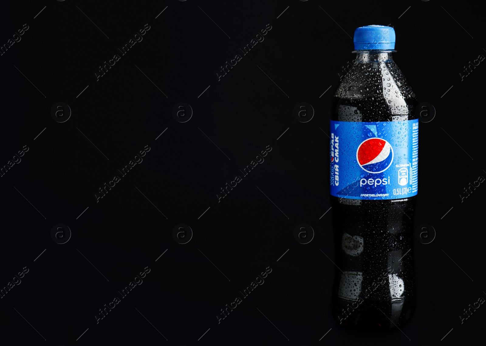 Photo of MYKOLAIV, UKRAINE - FEBRUARY 08, 2021: Plastic bottle of Pepsi with water drops on black background. Space for text