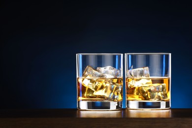 Photo of Whiskey with ice cubes in glasses on table. Space for text