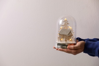 Photo of Man holding snow globe on light grey background, closeup. Space for text