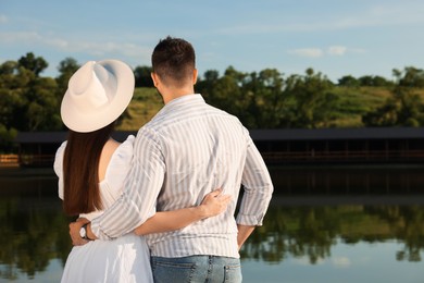 Romantic date. Couple spending time together near lake, back view with space for text