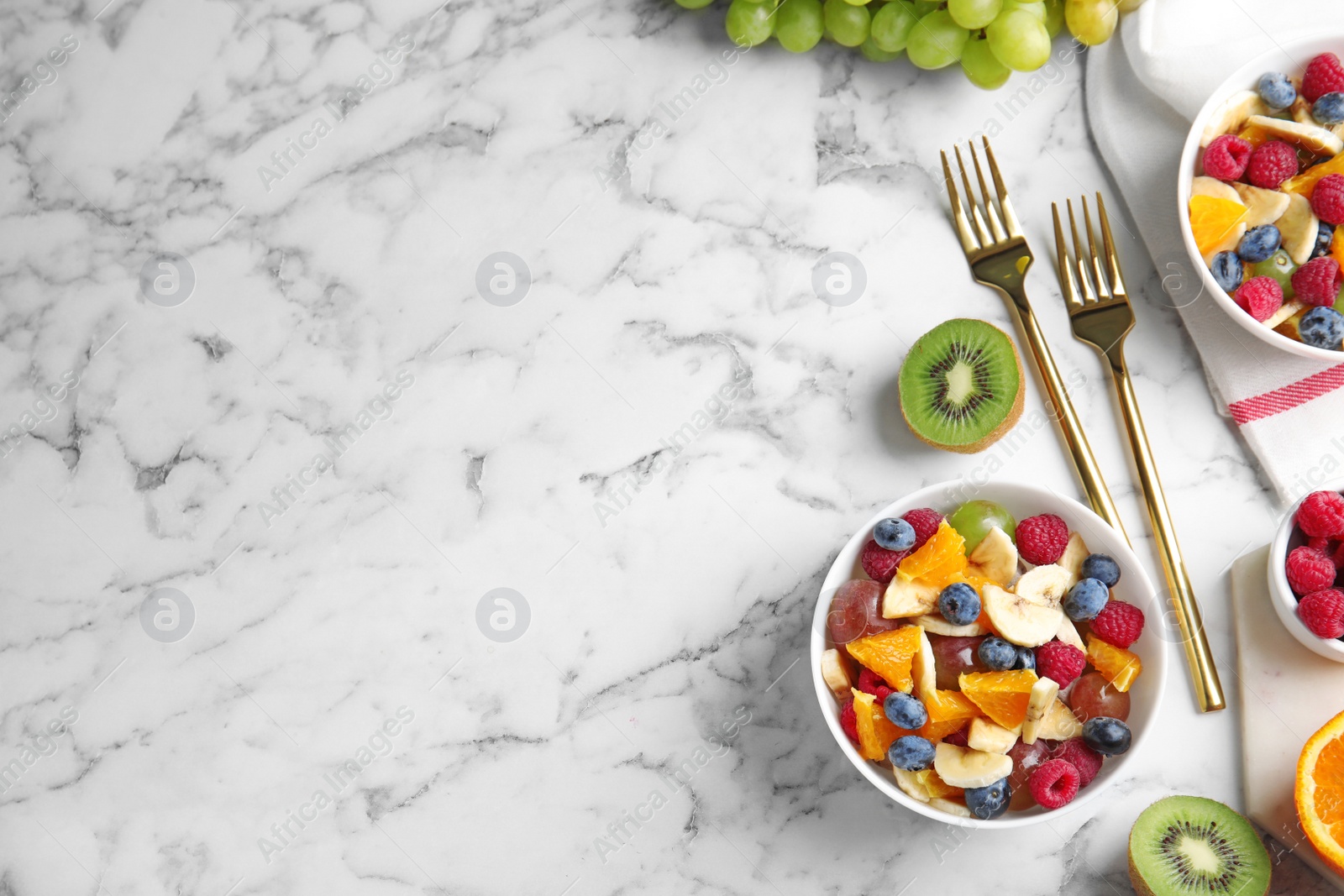 Photo of Fresh tasty fruit salad on white marble table, flat lay. Space for text