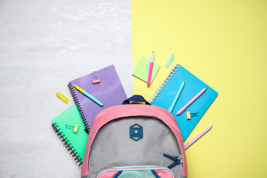 Photo of Flat lay composition backpack and stationery on color background
