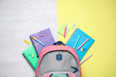 Flat lay composition backpack and stationery on color background