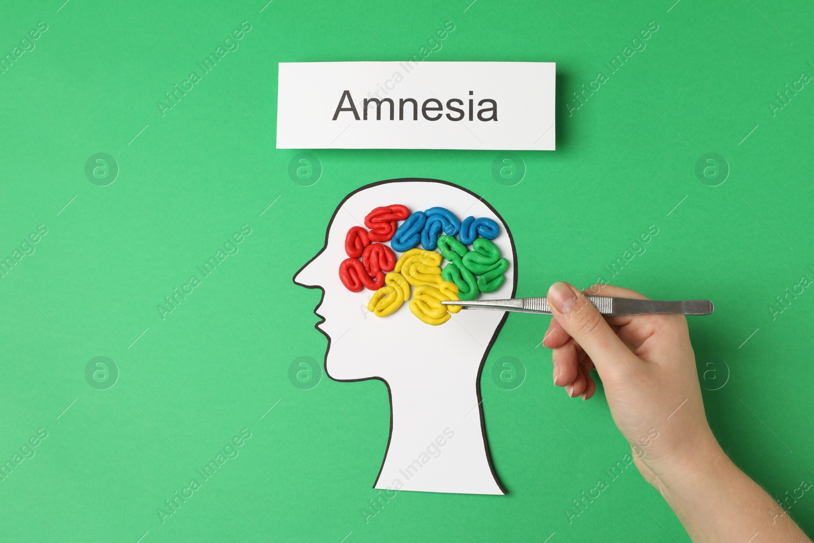 Photo of Woman making brain model with colorful plasticine on green background, top view. Amnesia concept