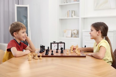 Cute children playing chess at table in room