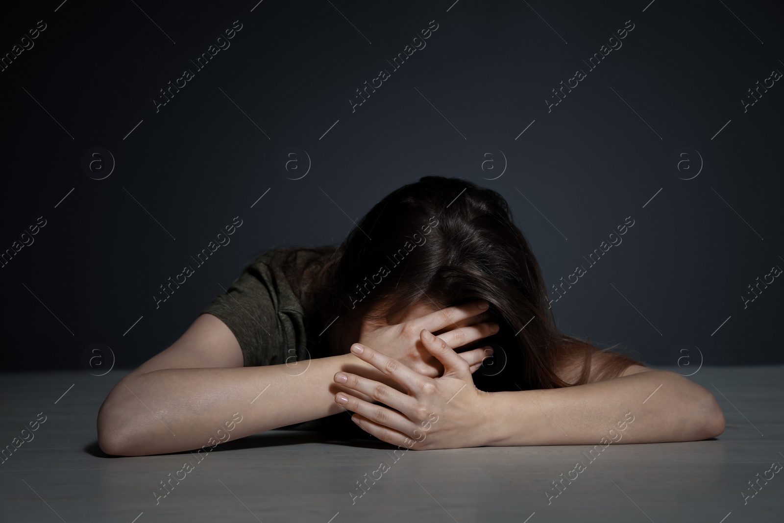 Photo of Young woman covering face while lying on floor indoors