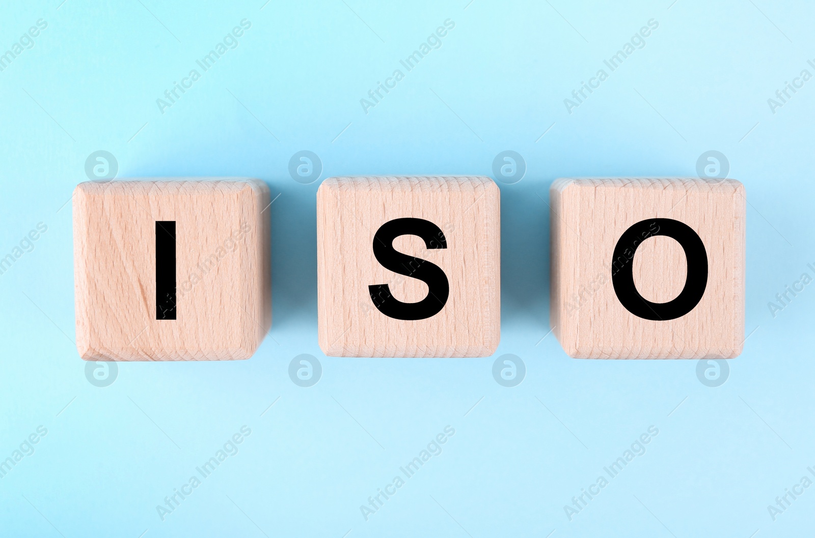Photo of International Organization for Standardization. Wooden cubes with abbreviation ISO on light blue background, top view