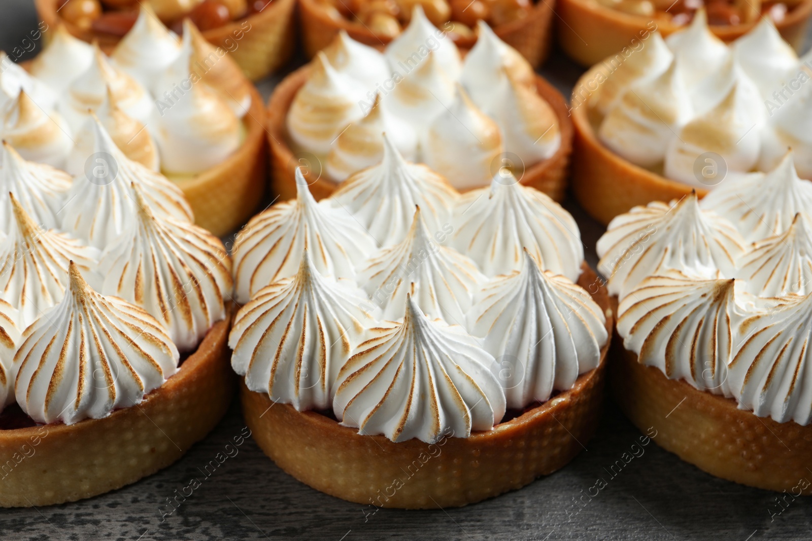 Photo of Many different tartlets on dark grey table, closeup. Tasty dessert