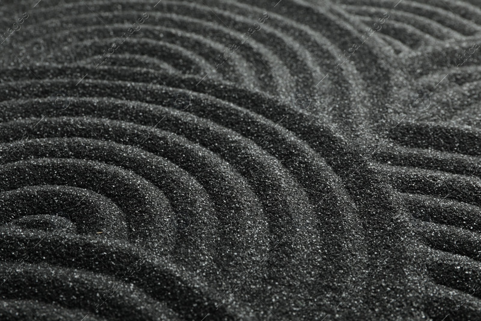 Photo of Black sand with beautiful pattern, closeup. Zen concept