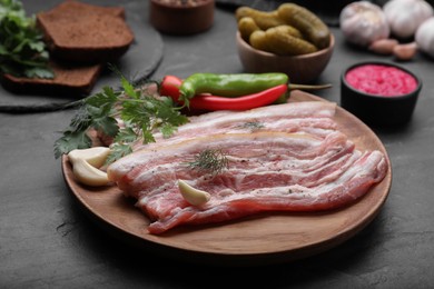 Photo of Tasty pork fatback and ingredients on black table, closeup