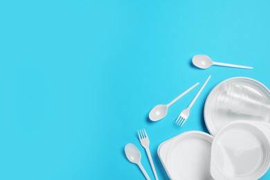 Photo of Disposable tableware on light blue background, flat lay. Space for text