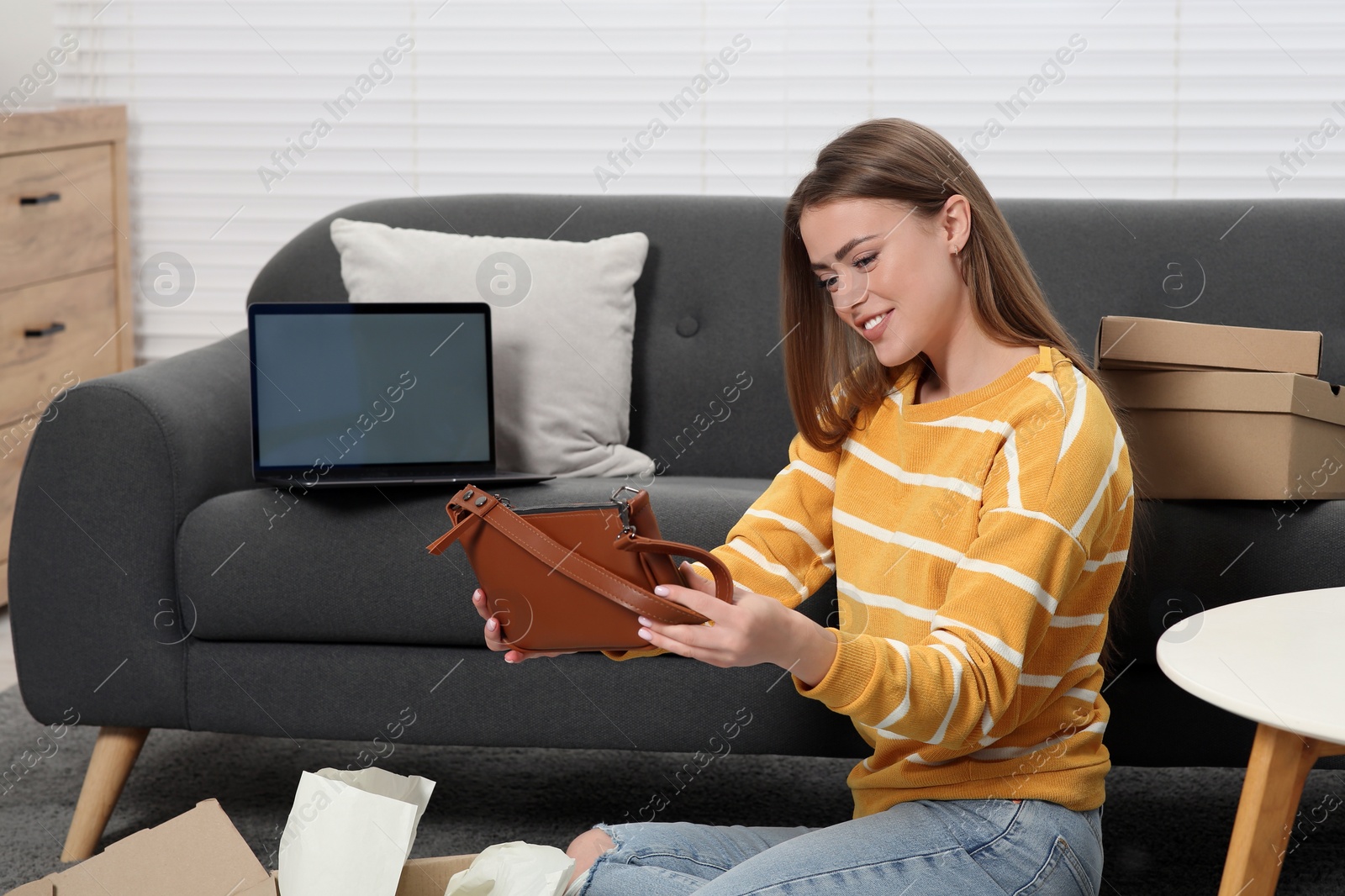 Photo of Happy woman with just unpacked new bag at home. Online store