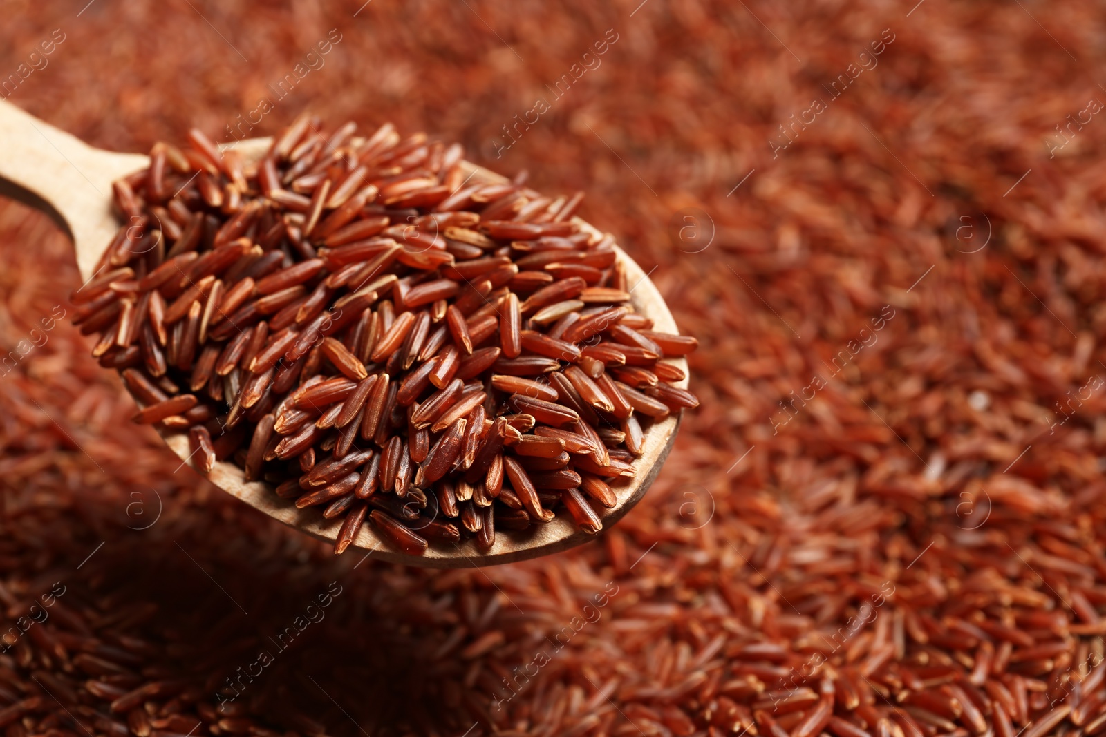 Photo of Brown rice in wooden spoon, closeup view