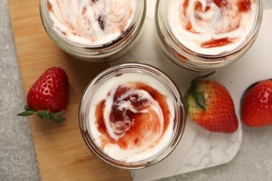 Photo of Tasty yoghurt with jam and strawberries on grey table, top view