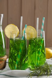 Glasses of refreshing tarragon drink with lemon slices on table