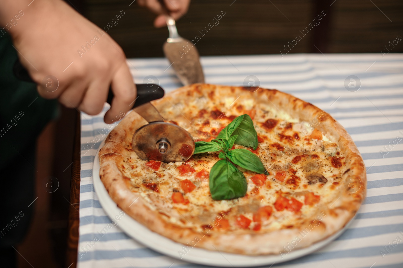 Photo of Man cutting tasty oven baked pizza on table, closeup