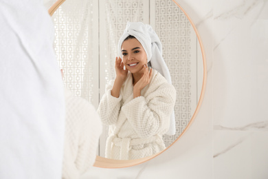 Young woman with hair wrapped in towel near mirror indoors