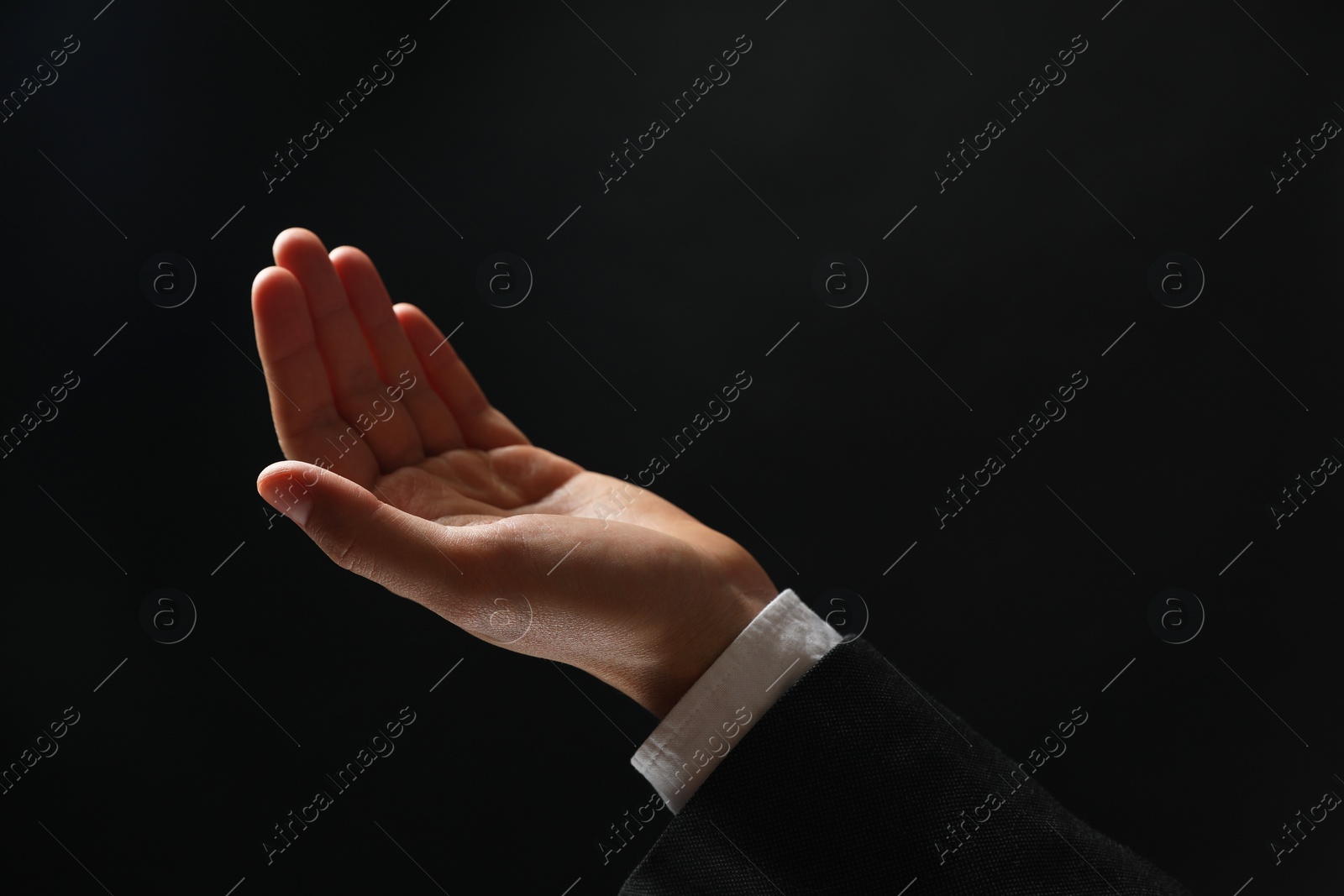 Photo of Man holding something in hand on black background, closeup. Space for text