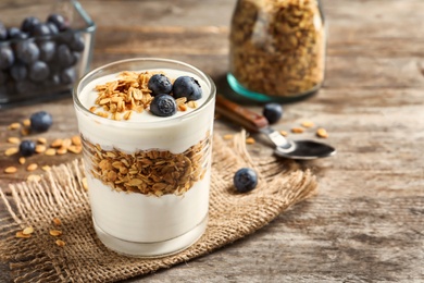 Glass with yogurt, berries and granola on wooden table