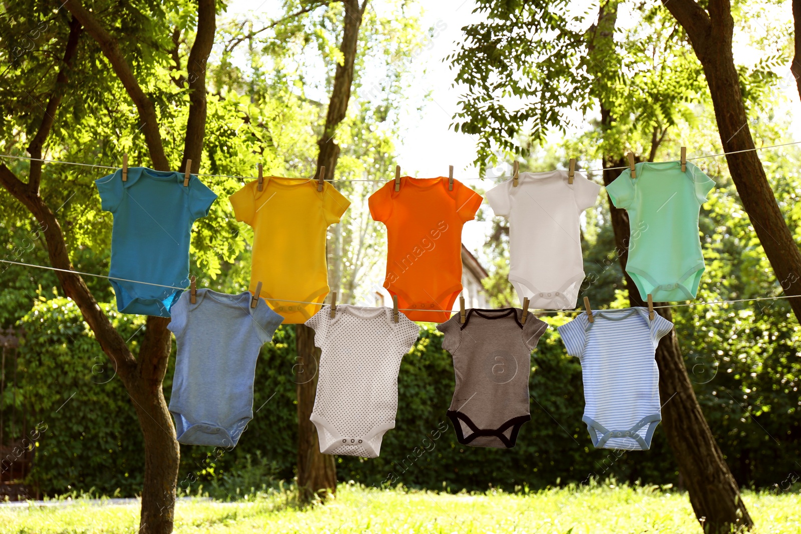 Photo of Colorful baby onesies hanging on clothes lines outside