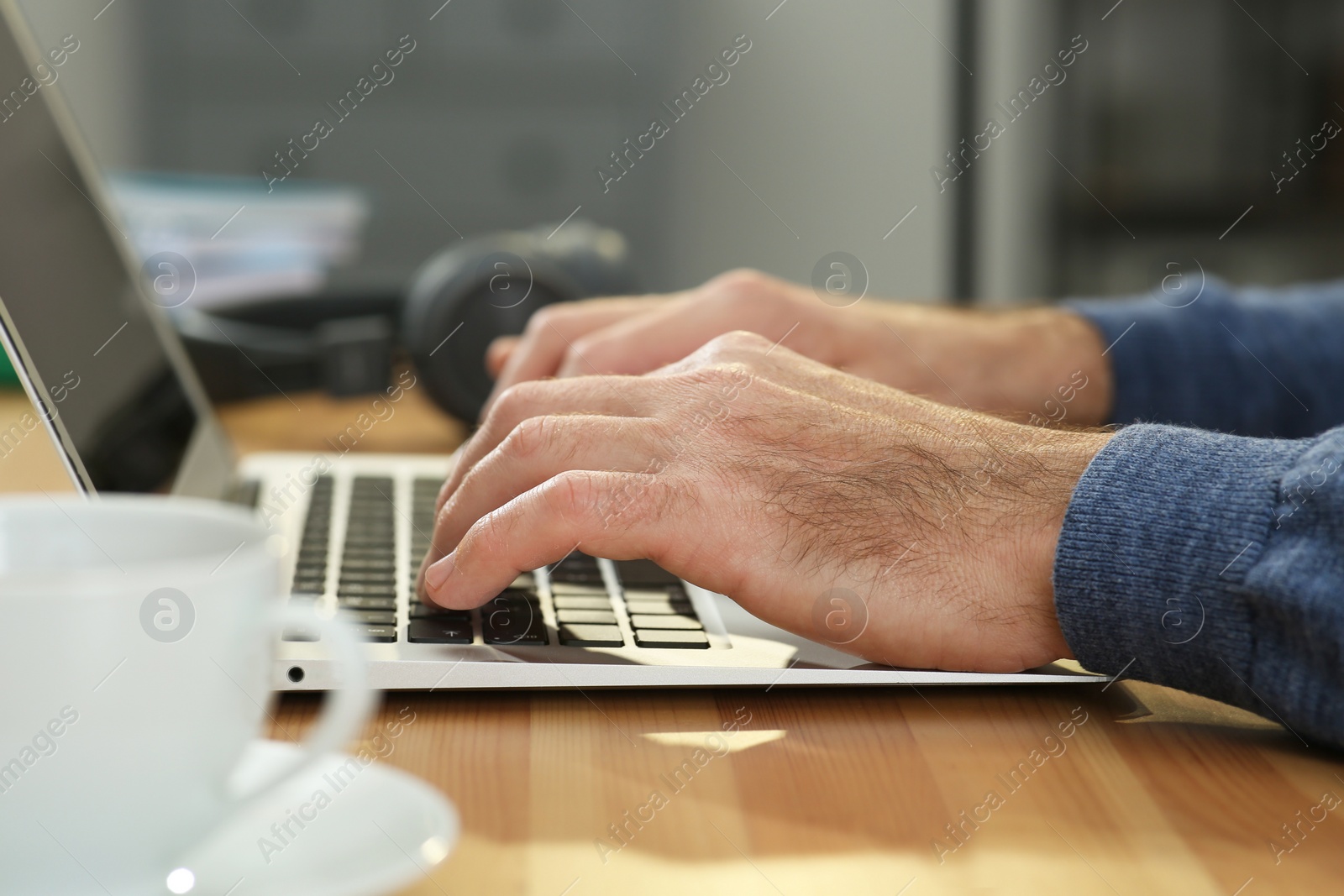 Photo of Man with laptop learning at wooden table indoors, closeup