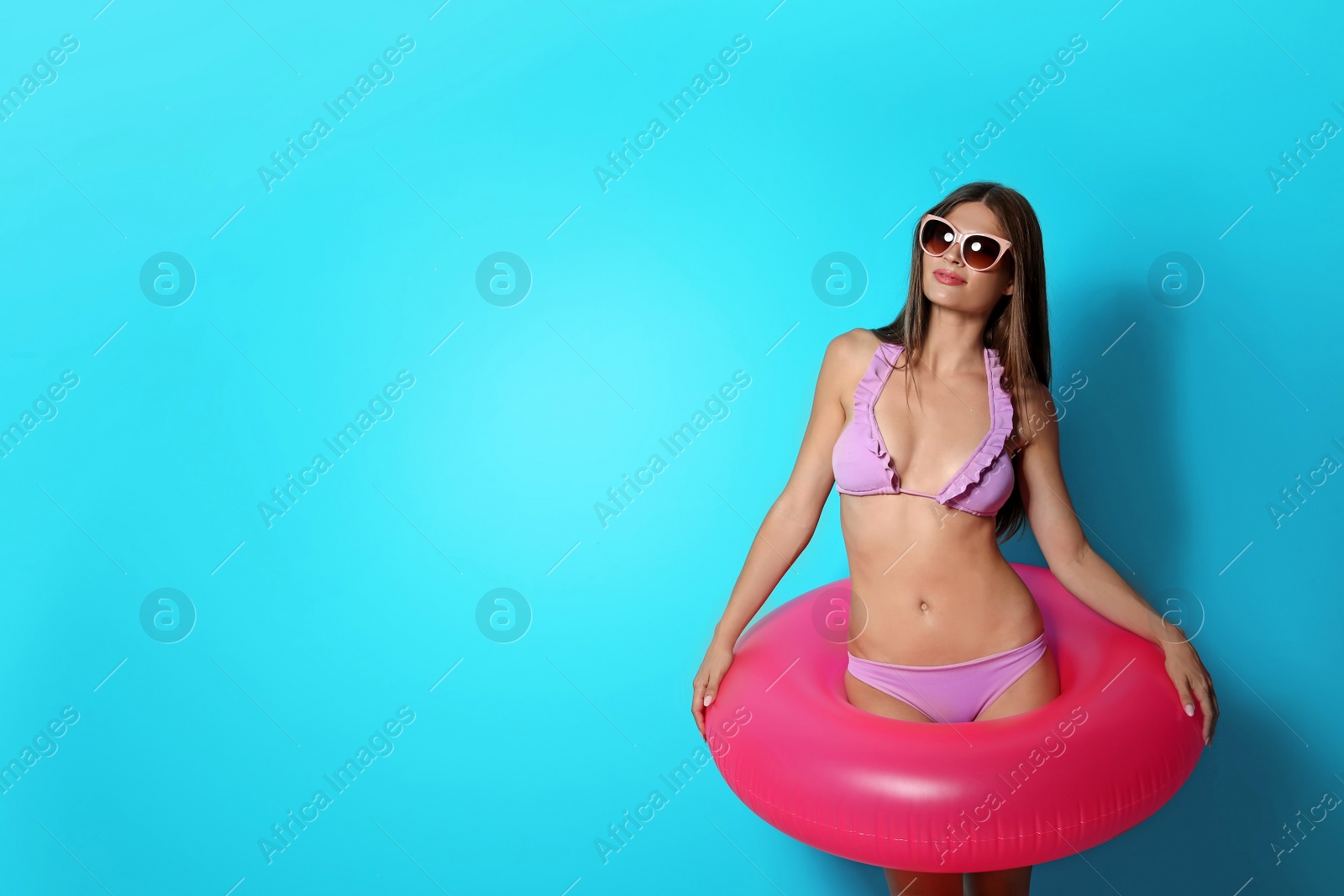 Photo of Sexy young woman in bikini with inflatable ring on color background