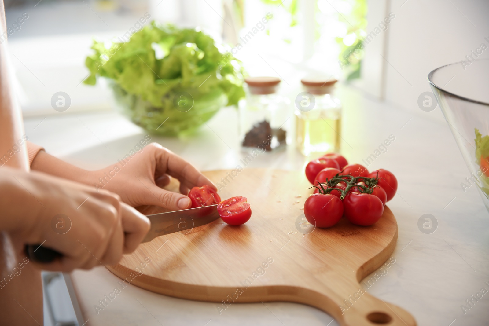 Photo of Young woman cooking at table in kitchen, closeup