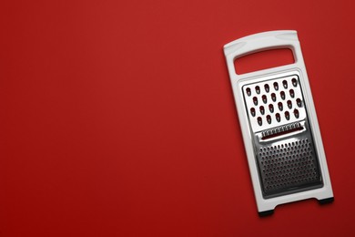 Photo of Modern grater on red background, top view. Space for text