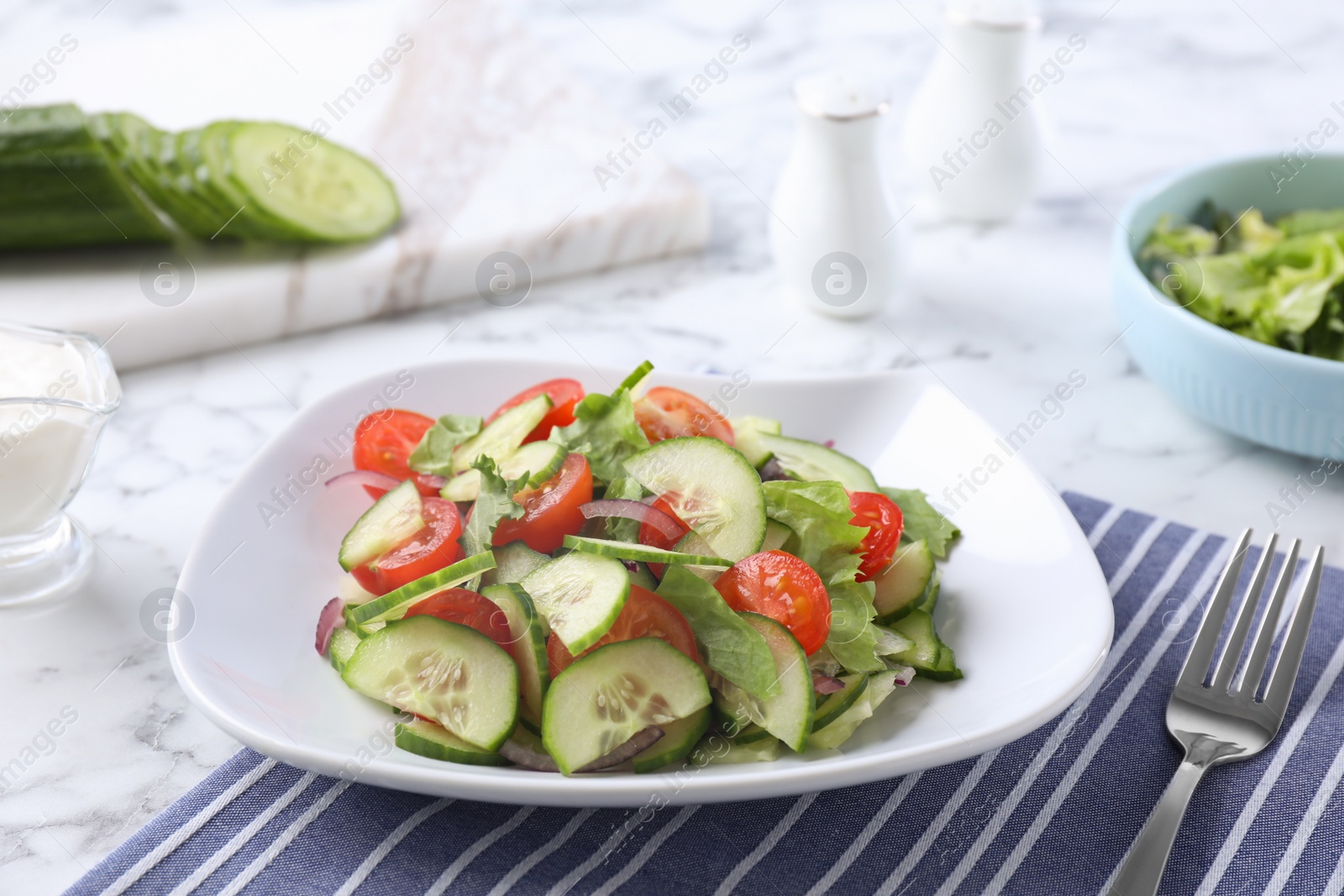 Photo of Plate of vegetarian salad with cucumber, tomato, lettuce and onion served on table