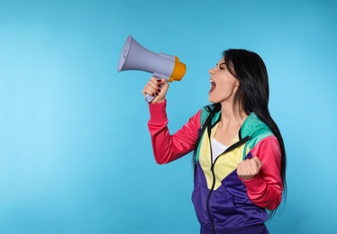 Photo of Portrait of emotional woman using megaphone on color background. Space for text