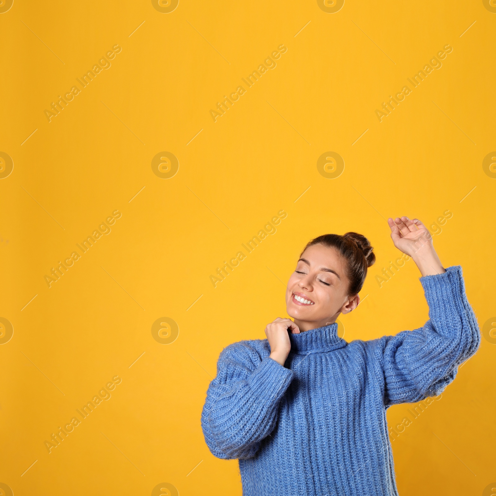 Photo of Young woman in stylish blue sweater on yellow background, space for text
