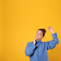 Young woman in stylish blue sweater on yellow background, space for text