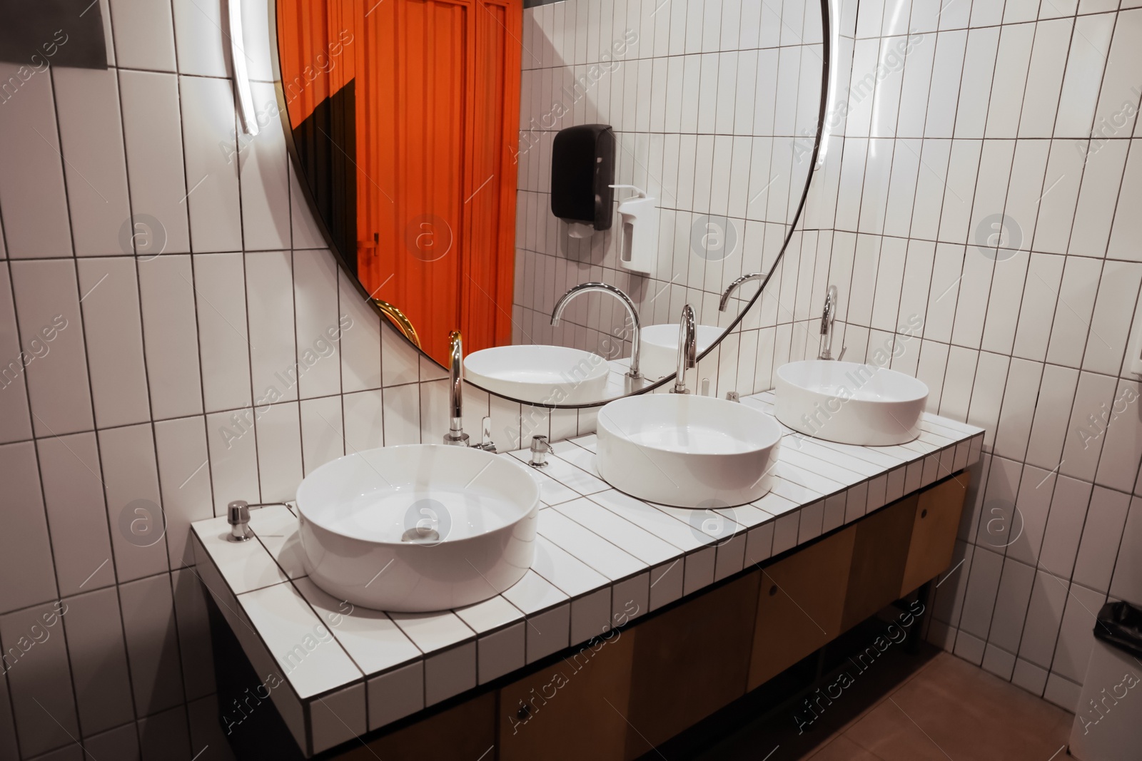 Photo of Public toilet interior with sinks and mirror