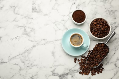 Coffee beans, powder and cup of drink on white marble table, flat lay. Space for text